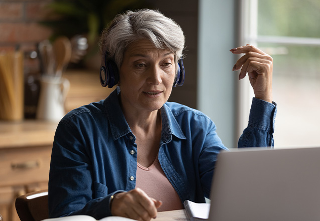 Woman wears headphones to watch presentation on laptop